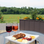 two glasses of wine beside a cheese plate on an outdoor patio table