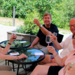 two couples holding up wine glasses sitting on muskoka lakes winery's patio