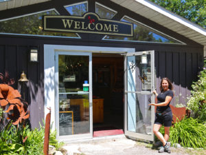 girl holding the store door open with a welcoming gesture