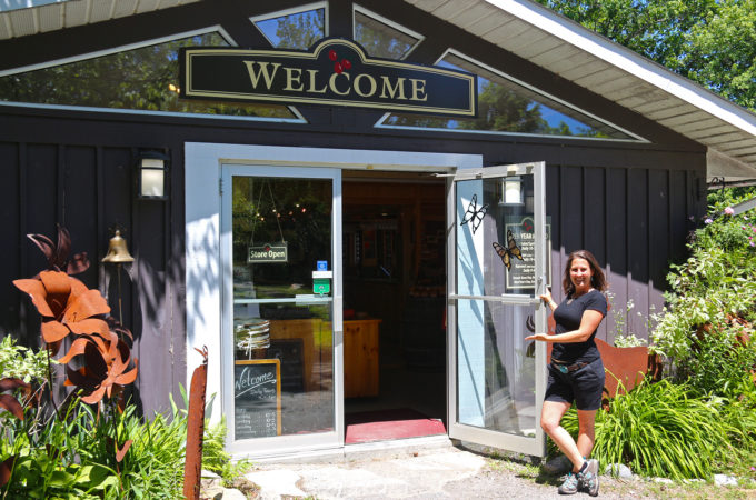 girl holding the store door open with a welcoming gesture