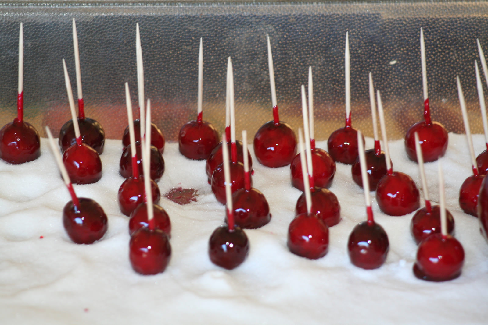 tray of candied cranberries with toothpicks sitting in a sugar bed