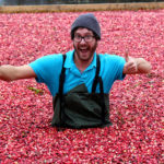 man in flooded cranberries with thumbs up