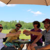 two couples touching glasses sitting on an outdoor patio in summer