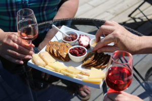 people sampling a plate of cheese, crackers, preserves while holding wine