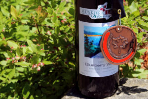 medal hanging on a bottle of blueberry wine against a background of immature blueberries