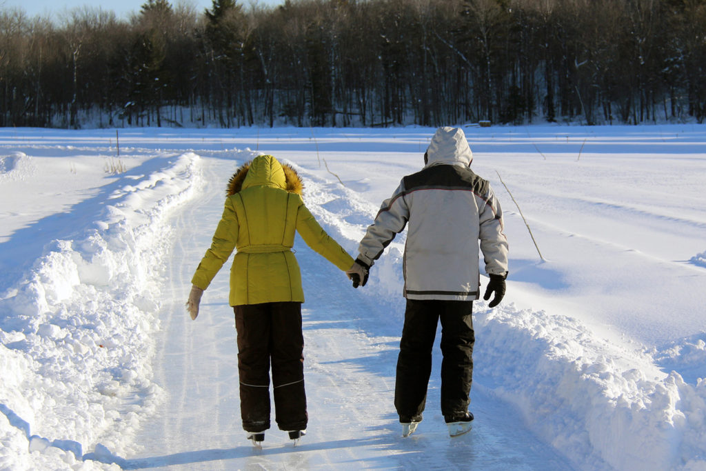 couple skating away on the ice trail holding hands