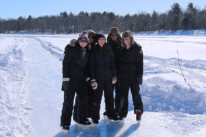 group of five people in skates standing on the ice trail