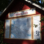 picture of trail head sign at johnston's cranberry marsh with green leaves all around