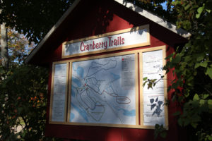 picture of trail head sign at johnston's cranberry marsh with green leaves all around