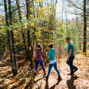 two girls and a guy hiking in the woods in autumn