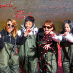 four smiling people tossing cranberries in the air while standing in floating cranberries