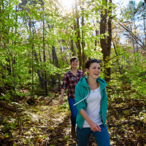 two smiling girls hiking through the woods