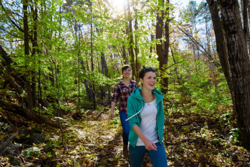 two smiling girls hiking through the woods