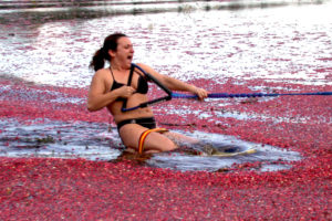young woman kneeboarding through floating cranberries