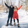 couple on snowshoes with hands in the air
