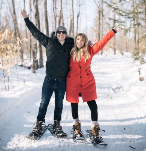 couple on snowshoes with hands in the air