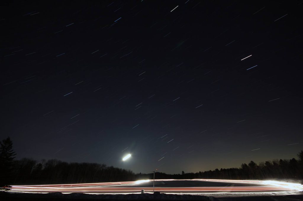 time lapse night photo showing light trails from equipment flooding the ice trail and star trails