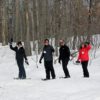 four people snowshoeing and waving