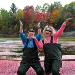 two women tossing cranberries in the air and laughing