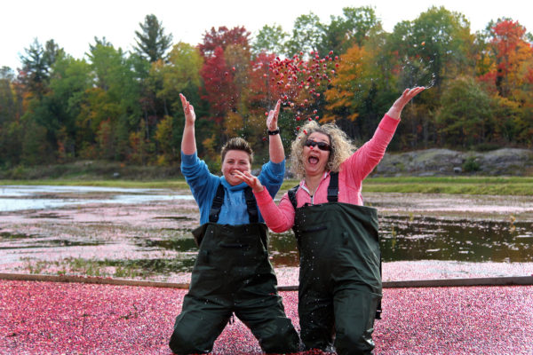 two women tossing cranberries in the air and laughing