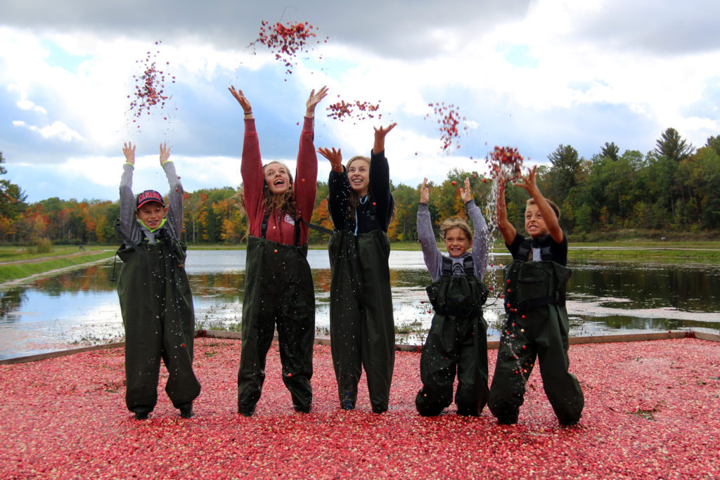 five kids laughing and tossing cranberries in the air