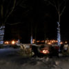 fire pit surrounded by muskoka chairs with ice trail in the background lit with torches for night skating