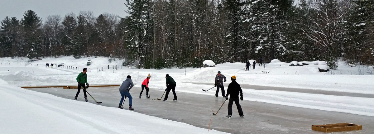 six people playing pond hockey on an outdoor rink