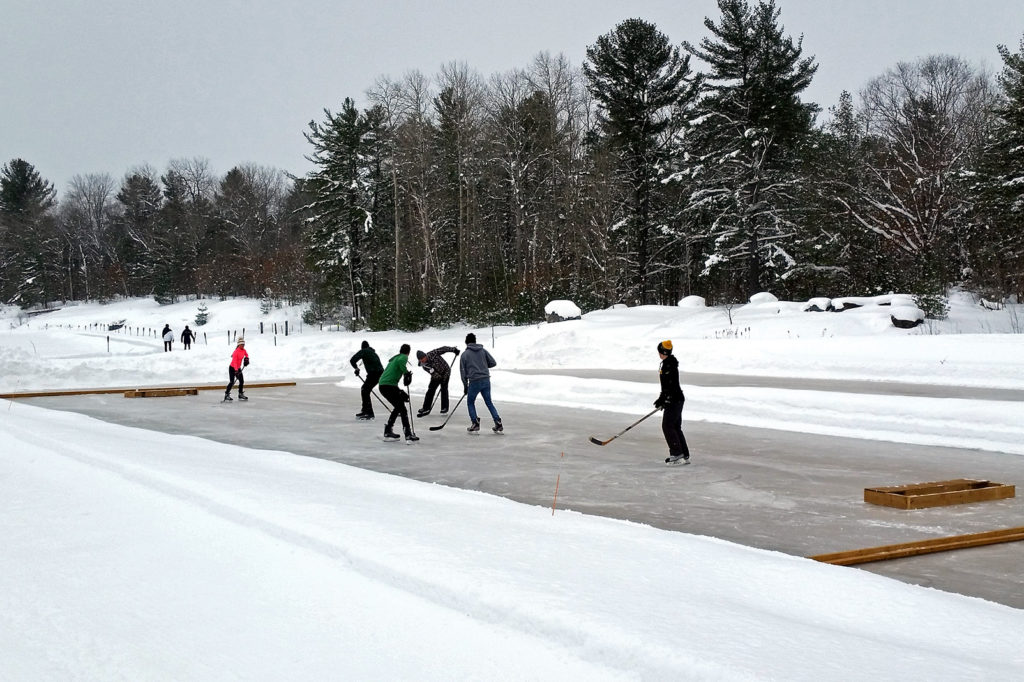 six people playing pond hockey on an outdoor rink