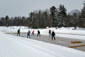 six people playing pond hockey on an outdoor rink