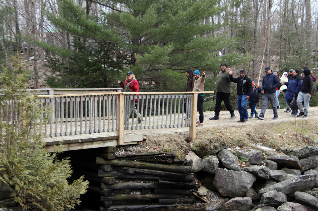 group of people walking across bridge on maple sugar bush tour