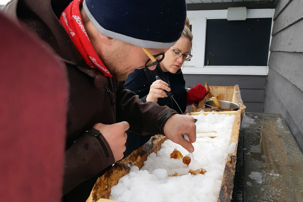 couple preparing maple taffy on snow