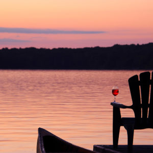 muskoka chair at sunset with glass of muskoka lakes wine spritzer