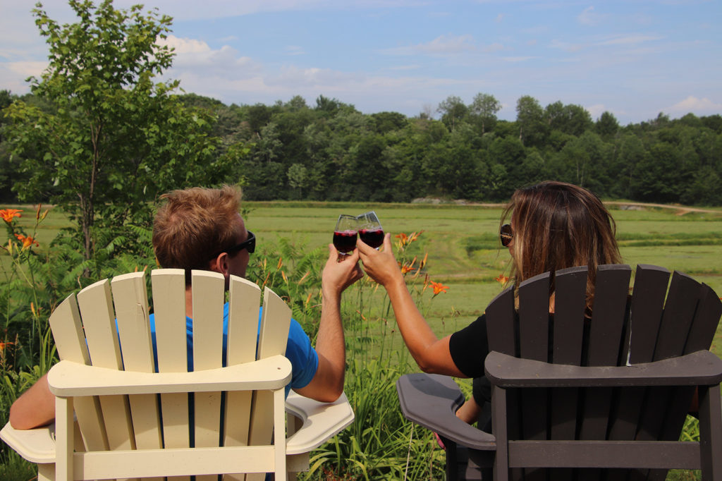 couple sitting in muskoka chairs holding wine