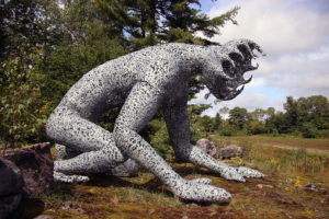 huge crouched metal sculpture overlooking a cranberry bog