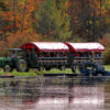 tractor pulled wagon tour with a cranberry picker in the foreground and fall trees in background