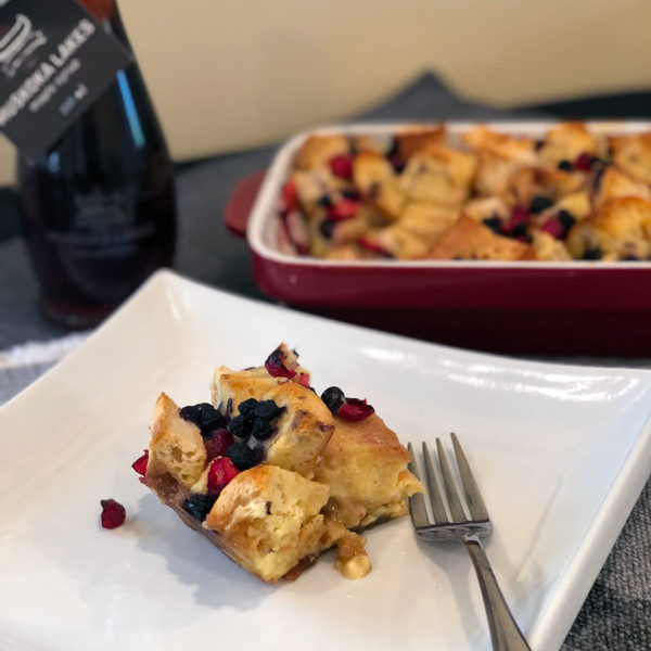 cranberry blueberry french toast bake on a plate with maple syrup in background