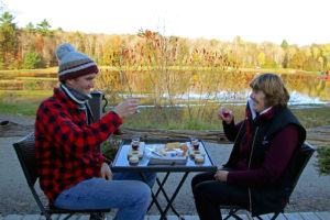 two people with wine and cheese on a patio with a view of water and trees