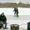 people in winter around a fire pit with skaters in the background