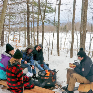 people around a fire pit in winter roasting marshmallows