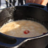 pot of cheese fondue with a floating cranberry