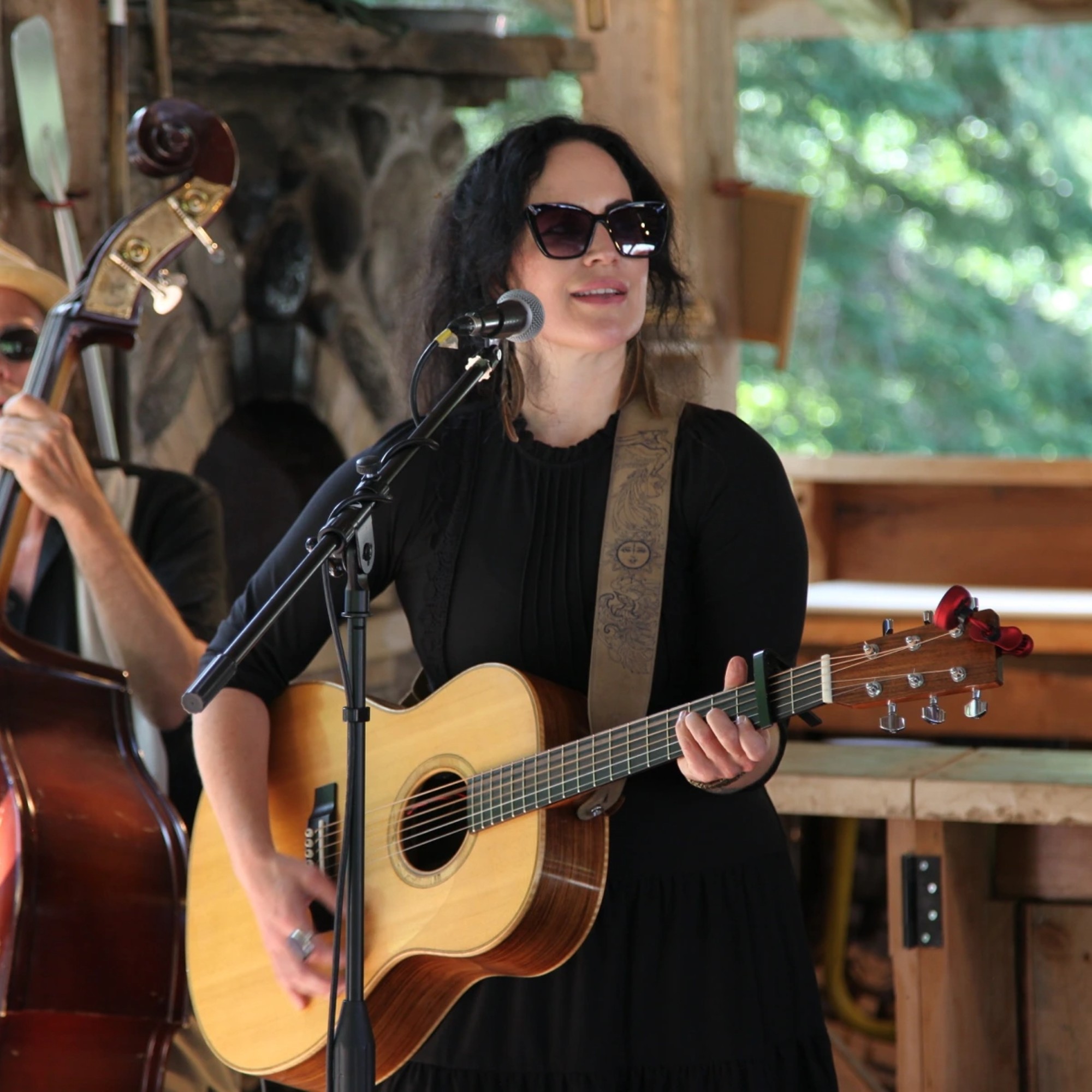 Christina Hutt playing her guitar while singing in a rustic setting