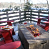 four muskoka chairs around an outdoor fire table with wine glasses and cheese plate
