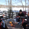 three people cheers with wine glasses around an outdoor fire table with Muskoka chairs