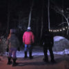 three people snowshoeing at night with headlamps