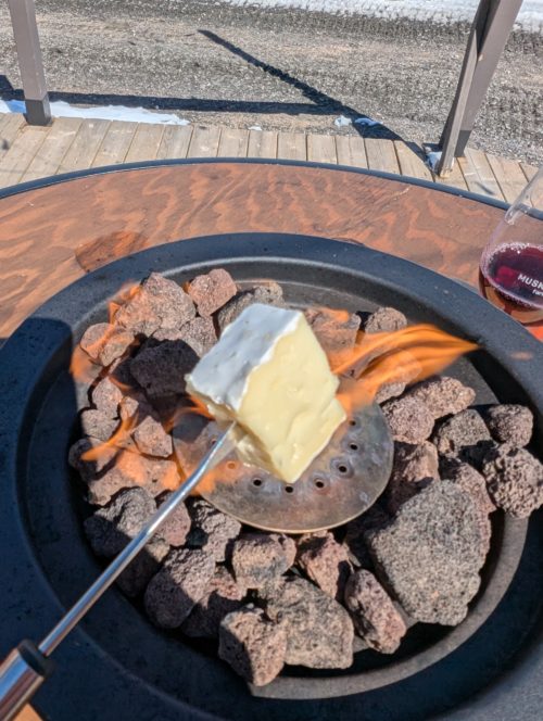 A brie cube being roasted over a flame